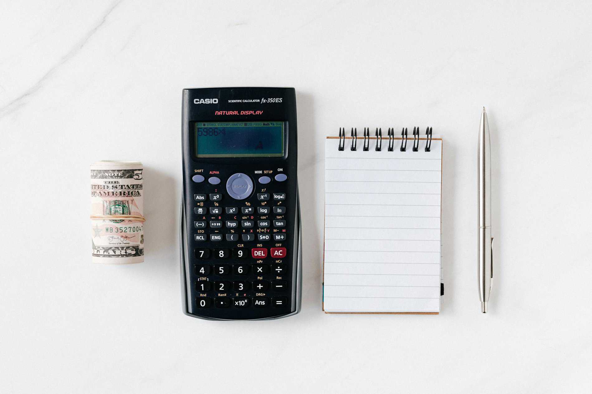 Composition of calculator with paper money and notebook with pen